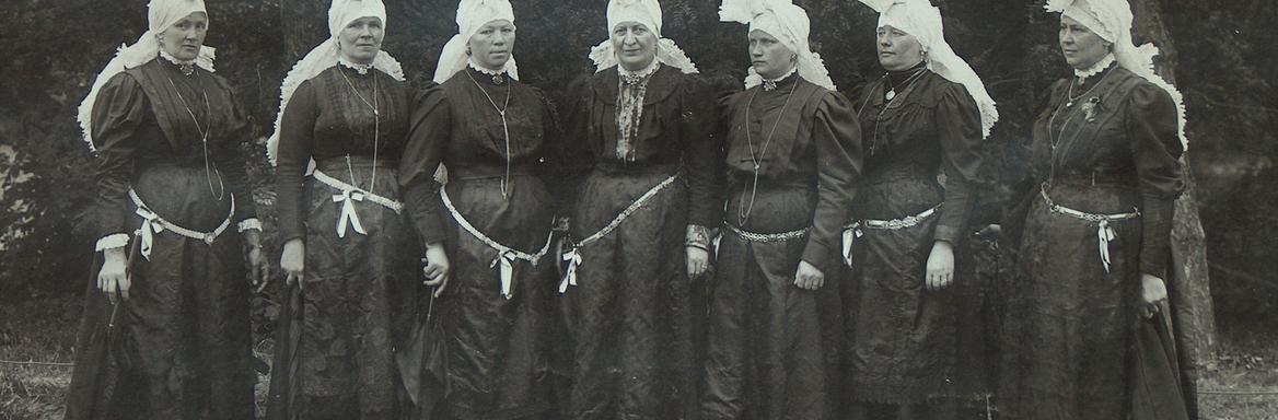 Skupina kostumiranih žena s pečami, vezanimi »na petelina«. Sprevod narodnih noš, Ljubljana, 1908 / Dokumentacija SEM.