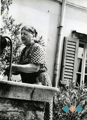 Nona Ana pri vodnjaku na domačem dvorišču leta 1970. Družinska zbirka Caharija.