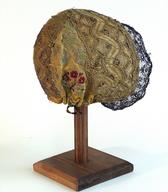 Utrjena, glavi prilegajoča se avba (kapa)  iz rumene brokatne svile z zlatimi kovinskimi nitkami, s krašenim čelnim in temenskim delom / Rož / iz zbirke SEM / foto: J. Žagar. 