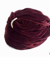 Ženska kapa v obliki turbana iz bordo rdečega gladkega žameta in okrasno kovinsko zaponko / Ljubljana / iz zbirke SEM / foto: J. Žagar. 