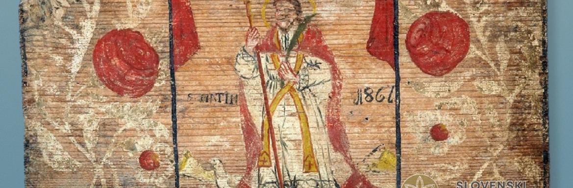 Na fotografiji je panjska končnica iz zbirke SEM, poslikana z motivom sv. Martina v škofovski opravi in z gosjo pri nogah.