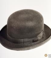 Moški polcilinder ali melona iz fine črne polsti, z močno utrjenim polkrožnim oglavjem in s trdimi krajci; v notranjosti odtis dunajskega proizvajalca in ljubljanskega prodajalca. Polcilinder je pred 2. svetovno vojno uporabljal poštni uradnik / Ljubljana / iz zbirke SEM / foto: J. Žagar. 