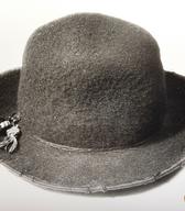 Moški klobuk z višjim okroglim oglavjem in širšimi, navzgor zasukanimi krajci; narejen iz debelega črnega sukna, z okrasno volneno vrvico in okraski. V notranjosti napis trgovca iz Ljubljane / Šentjakob v Rožu / iz zbirke SEM / foto: J. Žagar. 