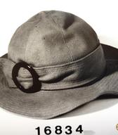 Ženski klobuk iz rjavega volnenega kosmatenega blaga, z okroglim priležnim oglavjem in mehkimi krajci; konfekcijski izdelek. V 60. letih 20. stoletja ga je nosila gimnazijska profesorica / Ljubljana / iz zbirke SEM / foto: J. Žagar. 