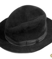 Moški klobuk iz črne klobučevine z daljšimi dlačicami, z mehkim, trikotno vtisnjenim oglavjem in mehkimi krajci. V notranjosti odtis kranjskega proizvajalca. Klobuk je bil kot nedeljsko pokrivalo v rabi okoli leta 1950 / Žeje pri Spodnjih Dupljah / iz zbirke SEM / foto: J. Žagar. 