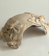 Žensko temensko pokrivalo iz umazano bele klobučevine, utrjeno z vstavljeno žico, z okrasnimi stiliziranimi cveti iz enakega tvoriva in elastiko za pritrjevanje; iz 50. let 20. stoletja / Ljubljana / iz zbirke SEM / foto: J. Žagar. 